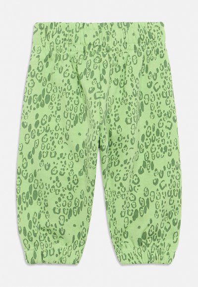 Zelené kalhoty s elastickým pasem a elastickými manžetami, zdobené tmavě zeleným abstraktním leopardím vzorem na světle zeleném pozadí.
