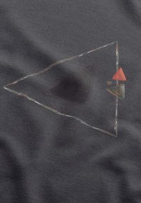 Donkergrijze stof met een driehoekpatroon, waarin een rode driehoek en een groene figuur zijn weergegeven, omrand met wit, met een lichte textuur.