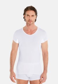 White cotton t-shirt with short sleeves and a V-neck design, featuring a smooth texture and fitted shape, displayed on a model.