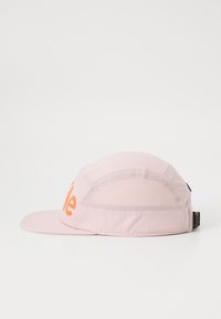 Roze pet met een gebogen klep, voorzien van een textielstof en oranje branding aan de voorkant. Ventilatiemeshpanelen aan de zijkanten.