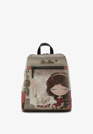 Mochila beige de cuero sintético con una ilustración de personaje y el texto "CONÓCETE A TI MISMO". Cuenta con un bolsillo delantero con cremallera y adornos decorativos.