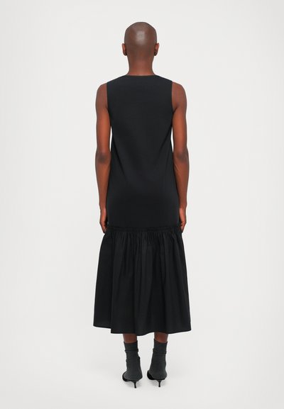 Schwarzes Kleid mit einem taillierten Oberteil und einem gerafften, fließenden Rock. Hergestellt aus einem glatten, weichen Stoff mit einem minimalistischen Design.
