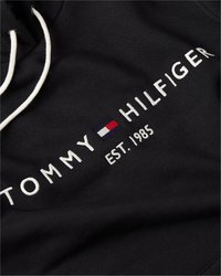 Juodas megztinis su balta išsiuvinėta užrašu "TOMMY HILFIGER" ir "EST. 1985", su raudona, balta ir mėlyna logotipo akcentu. Stori balti raišteliai.