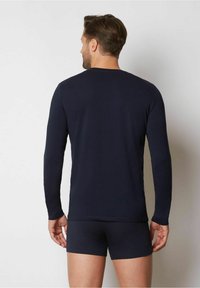 Marineblaues Langarmshirt kombiniert mit marineblauen Unterhosen, gefertigt aus glattem Stoff, mit klassischem Rundhalsausschnitt und taillierter Passform.