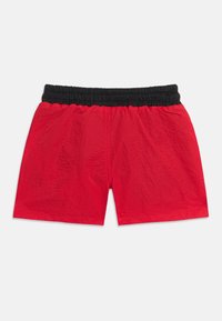 Κόκκινα σορτς με μαύρη ελαστική μέση, κατασκευασμένα από ελαφρύ ύφασμα, τοποθετημένα επίπεδα σε λευκό φόντο.