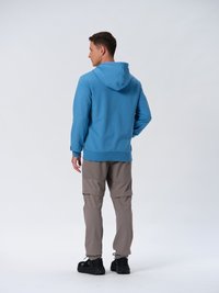 Felpa blu con cappuccio regolabile, abbinata a pantaloni cargo beige con tasche con zip. Scarpe sportive nere completano l'outfit.