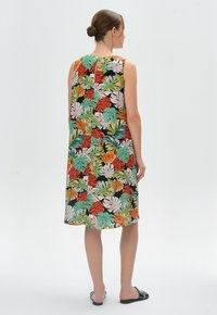 Ärmelloses Kleid mit einem lebhaften tropischen Blättermuster in Grün, Orange und Pink auf schwarzem Hintergrund. Glatte, weiche Stofftextur.
