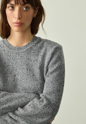 Grauer Strickpullover mit klassischem Rundhalsausschnitt, der ein strukturiertes Muster und Sprenkel in Blau und Schwarz aufweist.