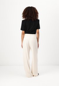 Black short-sleeve t-shirt and cream wide-leg trousers with pockets, featuring a smooth fabric texture and a tailored fit.