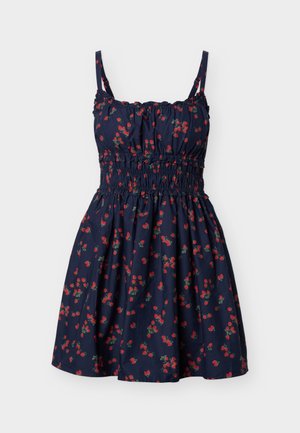 Navyblå ermeløs kjole med rødt jordbærtrykk, smocked midje og rysjekantet halslinning, knelang med tynne skulderstropper.