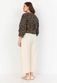 Cropped, black and beige leopard print blouse with three-quarter sleeves paired with cream wide-leg cargo pants and nude flats.