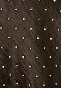 Tamno smeđi materijal s glatkom teksturom, sa ravnomjerno raspoređenim srebrnim metalnim zakovicama na površini, stvarajući uzorak.