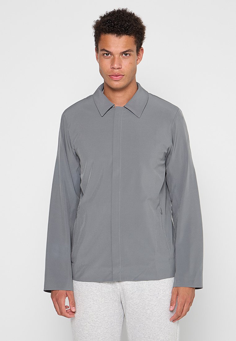 Graue leichte Jacke mit langen Ärmeln, einem Kragen und geradem Schnitt. Verfügt über Seitentaschen und eine glatte, matte Oberfläche.
