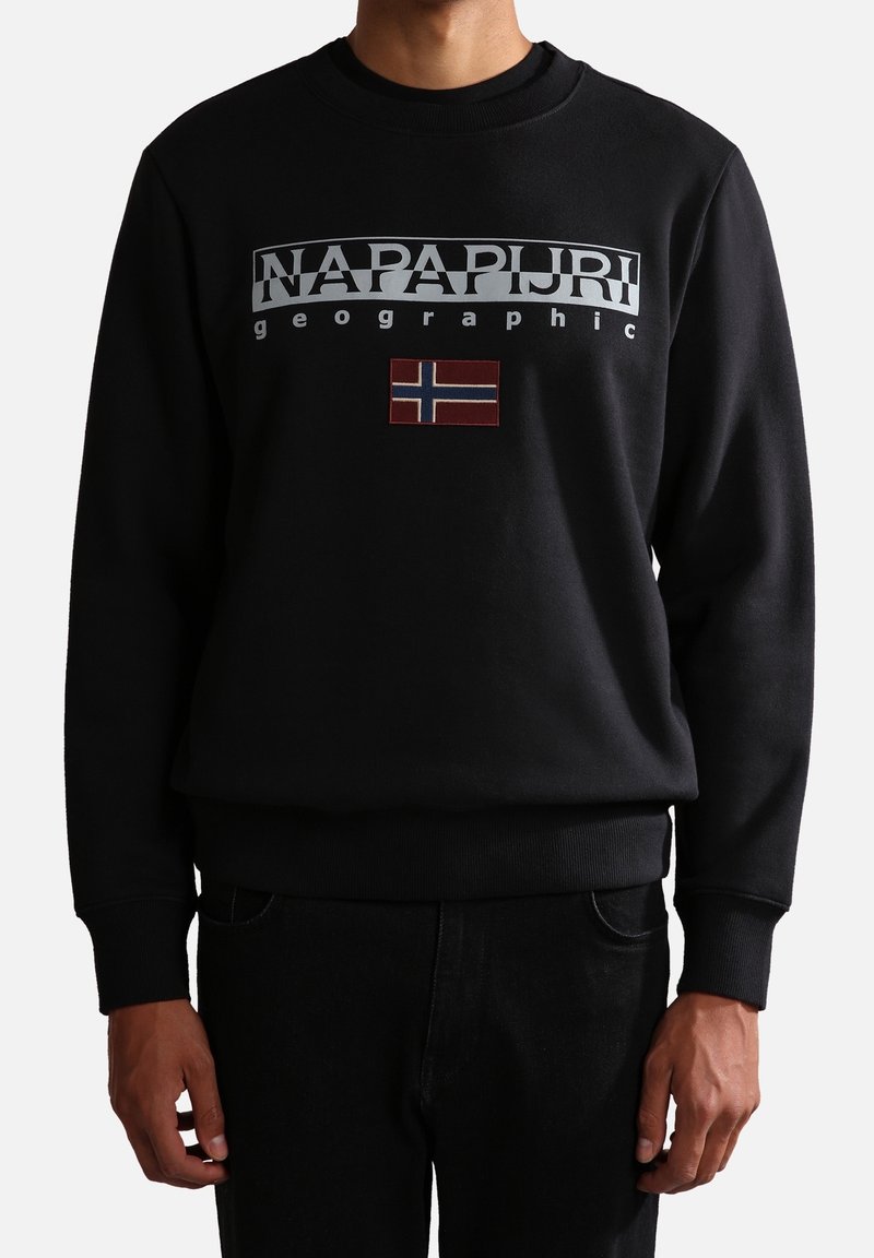Sweat-shirt noir avec le texte "NAPAPIJRI geographic" et un petit écusson du drapeau norvégien centré sur la poitrine, porté par une personne debout.