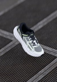 Men's running shoe with a black and white mesh upper, neon green accents, padded collar, and thick white sole. Features lace-up closure.