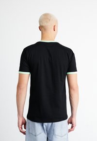Black short-sleeve t-shirt with a mint green ribbed collar and cuff accents, made of a smooth cotton material. Back view displayed.