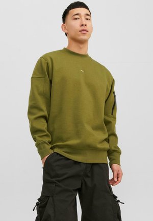 Olivgrüner Sweatshirt mit Rundhalsausschnitt, gerippten Bündchen und einer Reißverschlusstasche am linken Arm. Kombiniert mit schwarzen Cargo-Hosen.