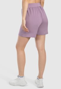 Pantalones cortos deportivos de color lila con una cinturilla elástica, hechos de material elástico. Los pantalones cortos tienen una textura suave y una longitud por encima de la rodilla.