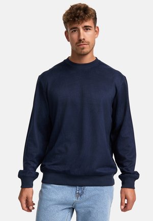 Mörkblå sweatshirt med rundad halsringning, långa ärmar, ribbade muddar och strukturerad tyg. Matchas med ljusblå jeans.