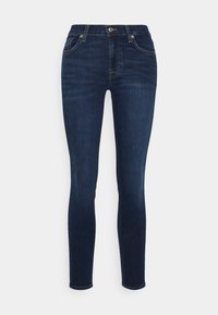 Dark blue skinny jeans made of denim, featuring a five-pocket design, metal button closure, and slight fading on thighs for texture.