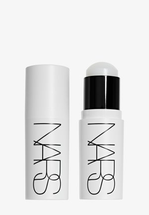 Stick cosmetico cilindrico bianco NARS con cappuccio nero rimosso, che mostra una punta arrotondata del prodotto all'interno del contenitore.