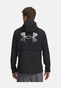 Schwarze leichte Jacke mit Kapuze, ausgestattet mit einem schrägen, reflektierenden Logo auf dem Rücken und elastischen Bündchen für eine enge Passform.