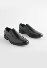 Crne kožne cipele na slip-on s glatkom završnom obradom, izduženim oblikom, suptilnim detaljima šivanja i niskim petama. Idealne za formalnu odjeću.
