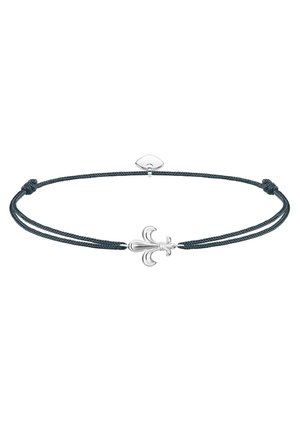 Bracelet cordon noir ajustable avec un charm fleur-de-lis en argent centré et un petit cœur en argent près du fermoir.