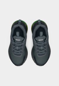 Ζευγάρι γκρι αθλητικών παπουτσιών με πλέξη από δίχτυ, γκρι κορδόνια, θηλιές έλξης και πράσινες διαφανείς λεπτομέρειες στη φτέρνα, σε θέα από ψηλά.