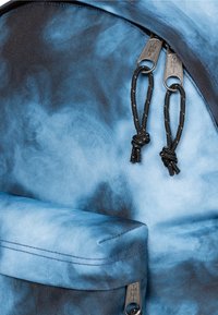 Zaino a sfumatura blu con accenti neri, tessuto dalla texture liscia, doppi cursori per la cerniera e chiusure con cordoncino nero annodato.