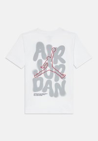 Camiseta de algodón blanca con un diseño de "AIR JORDAN" pintado con spray en gris, con una silueta contornada en rojo de un jugador saltando y texto debajo.