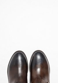 Chaussures en cuir marron à texture lisse, bout arrondi et accents contrastants en marron foncé. Caractérisées par un léger brillant et des bords surpiqués.
