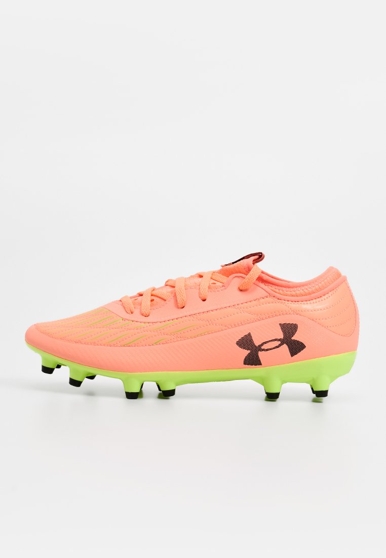 Botte de football rose vif avec une tige texturée, logo Under Armour noir et semelle verte avec des crampons moulés pour une meilleure traction.
