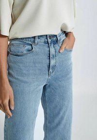 Heledad sinine denim teksad, millel on lõdvestatud istuvus, kõrge vöökoht ja viie taskuga disain. Omab lukuga pärgniit ja vöökoht vööde jaoks. 