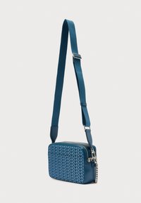 Μπλε τσάντα χιαστί με δομημένο ορθογώνιο σχήμα, με διακοσμητικό εμπρός μέρος, κλείσιμο με φερμουάρ και ρυθμιζόμενο λουράκι. Ασημένιες μεταλλικές λεπτομέρειες.