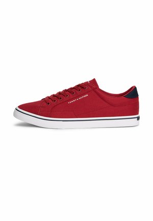 Zapatilla deportiva baja roja con suela blanca, detalle negro en el talón, diseño con cordones y texto "Tommy Hilfiger" en el lateral.