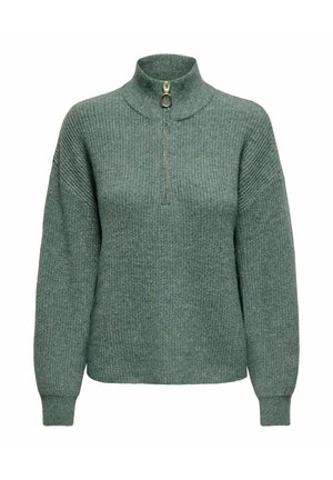 Ein grüner Strickpullover mit hohem Kragen und einem halben Reißverschluss, der eine gerippte Textur und überschnittene Schultern für eine lässige Passform aufweist.