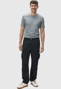 Grijze korte mouwen t-shirt gecombineerd met zwarte cargobroek met zijzakken en een comfortabele pasvorm, aangevuld met witte sneakers.