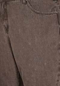 Pantalon en denim marron avec une texture lisse, featuring un design classique à cinq poches et un détail de couture visible.
