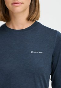 Marineblaues Langarmshirt aus strukturiertem Stoff, mit einem kleinen weißen "NORTH BEND"-Logo auf der Brust und einem runden Ausschnitt.
