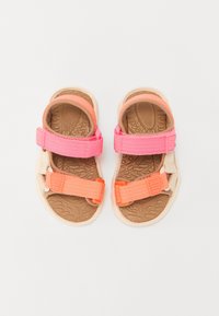 Kirkas monivärinen sandaalit, joissa on vaaleanpunaiset ja oranssit hihnat, teksturoidut ruskeat pohjat ja säädettävät sulkemiset. Kevyt muotoilu mukavuutta varten.