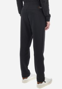 Zwarte sweatpants van zachte stof, met een relaxte pasvorm en een elastische tailleband, voorzien van een klein merkembleem op de achterkant.