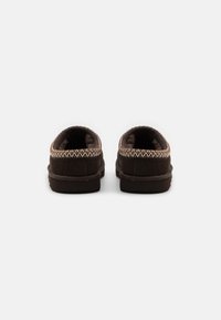Chaussures de style mocassin marron en suède, dotées d'un intérieur douillet et d'une couture décorative le long du col.