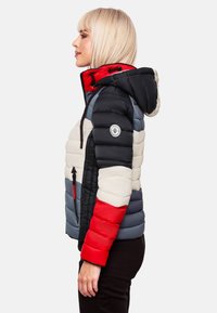 Veste rembourrée avec un design multicolore en noir, rouge, gris et crème. Comprend une capuche et des poches latérales avec des fermetures éclair.