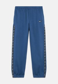 Μπλε φόρμα από βαμβακερό μείγμα, με ελαστική ζώνη μέσης, μανσέτες στα πόδια και μαύρες πλαϊνές ρίγες με επαναλαμβανόμενο κείμενο στολίσματος.