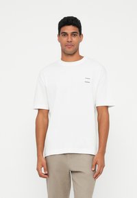 White cotton t-shirt with short sleeves, featuring a small black "Samsøe" logo on the chest. Casual fit with a round neckline.