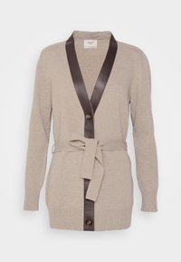 Pletený kardigan ve světle béžové barvě, s kontrastním tmavě hnědým koženým šálovým límcem, opaskem na zavázání a jednořadovým zapínáním.