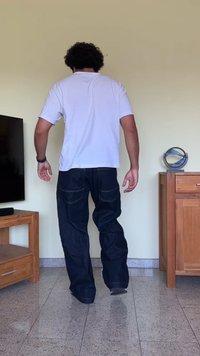 Μπλε τζιν παντελόνι με φαρδιά εφαρμογή, ορατές ραφές και πολλές τσέπες, συνδυασμένο με ένα απλό λευκό μπλουζάκι. Στοιχεία φόντου από ξύλο και πέτρα.