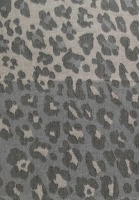 Tkanina s leopard uzorkom koja sadrži tamnosive i svijetlosmeđe tonove. Dizajn uključuje različite oblike i veličine mrlja na teksturiranoj površini.
