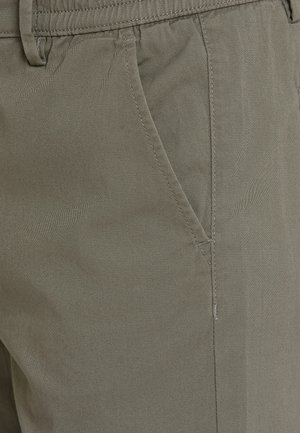 Kaki byxor gjorda av mjukt tyg, med regular fit, sidfickor och subtila sömdetaljer som visar en slät textur.